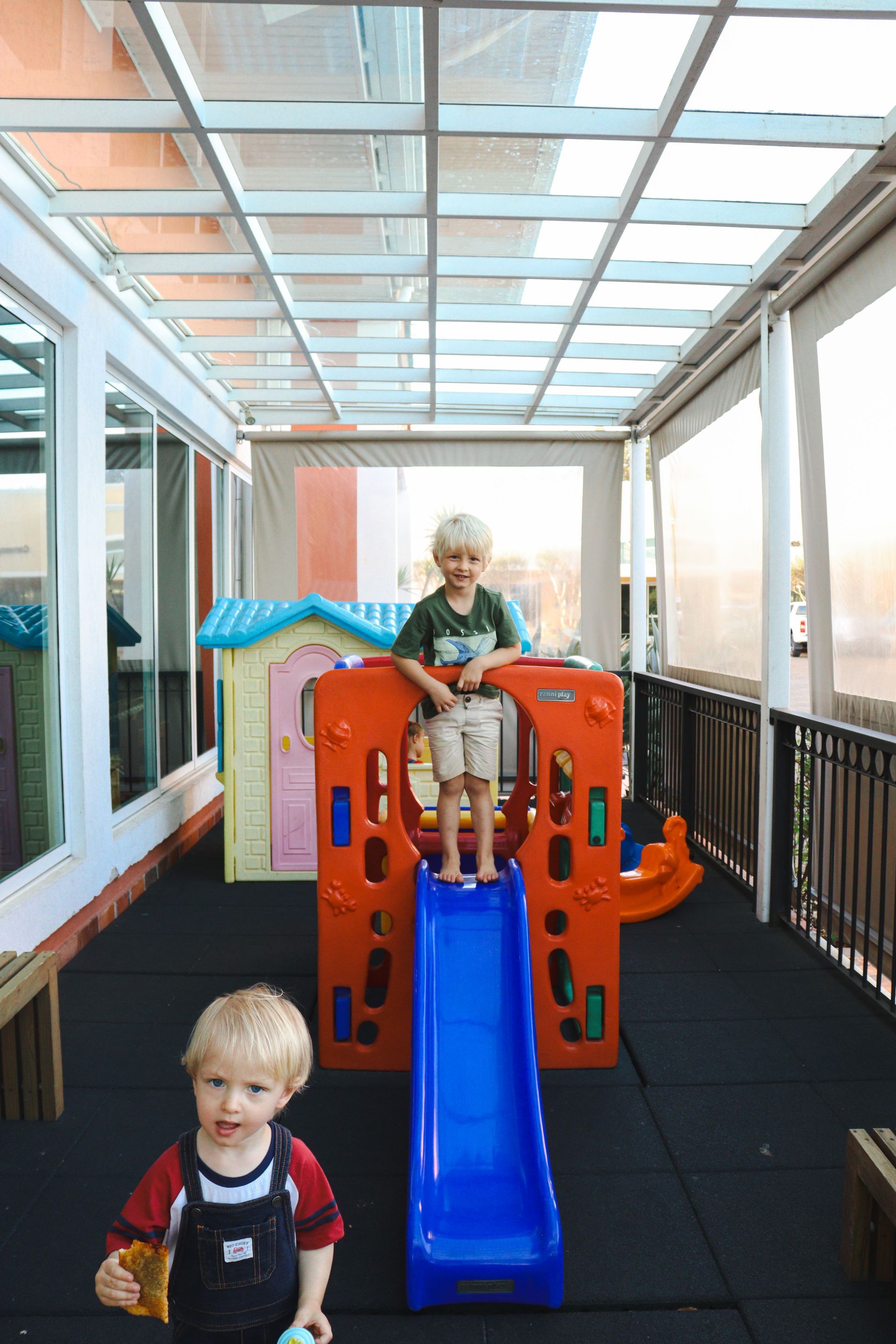 Dois meninos estão brincando em um playground com escorregador.