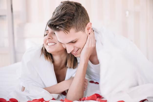 Um homem e uma mulher estão deitados em uma cama com pétalas de rosa.