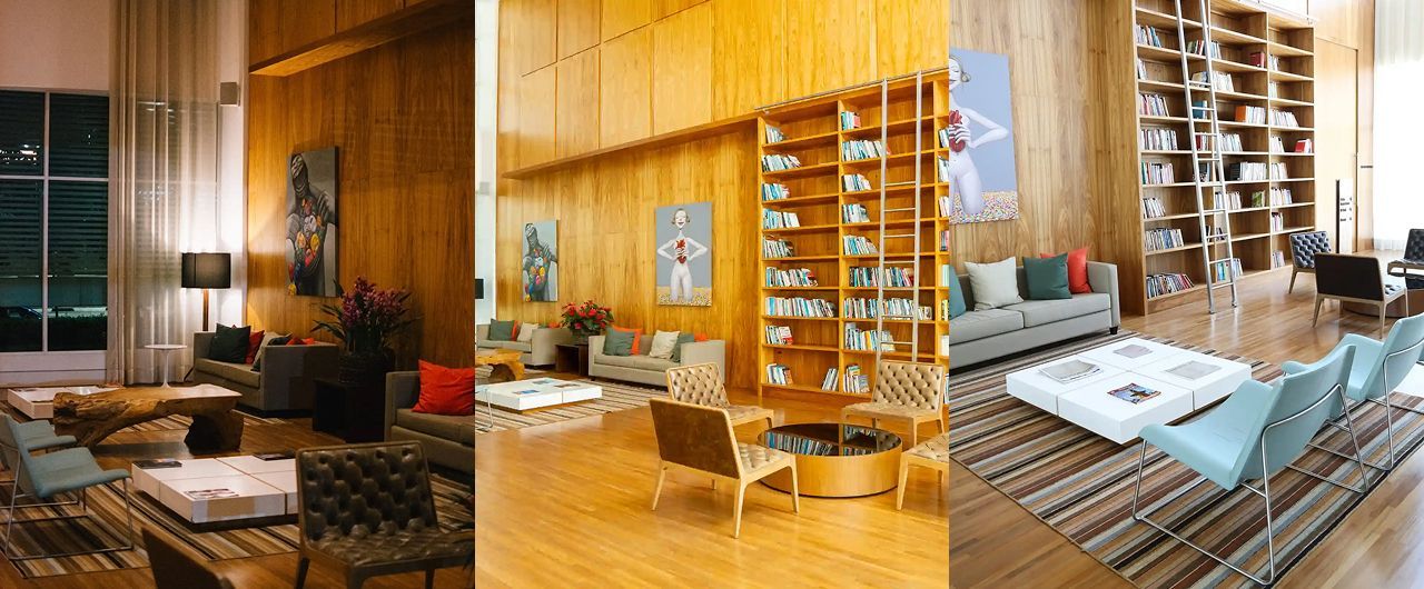 Sala de estar com painéis de madeira, várias áreas de estar, uma estante de livros e grandes janelas.