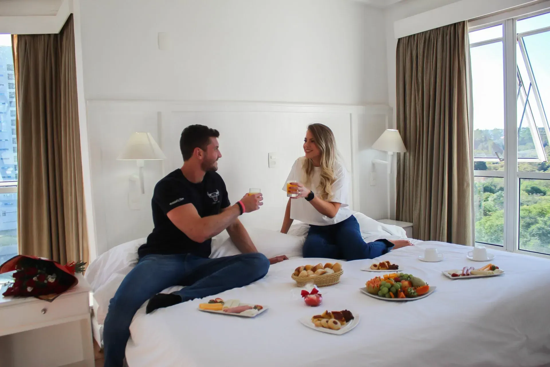 Duas pessoas estão brindando com café da manhã na cama.