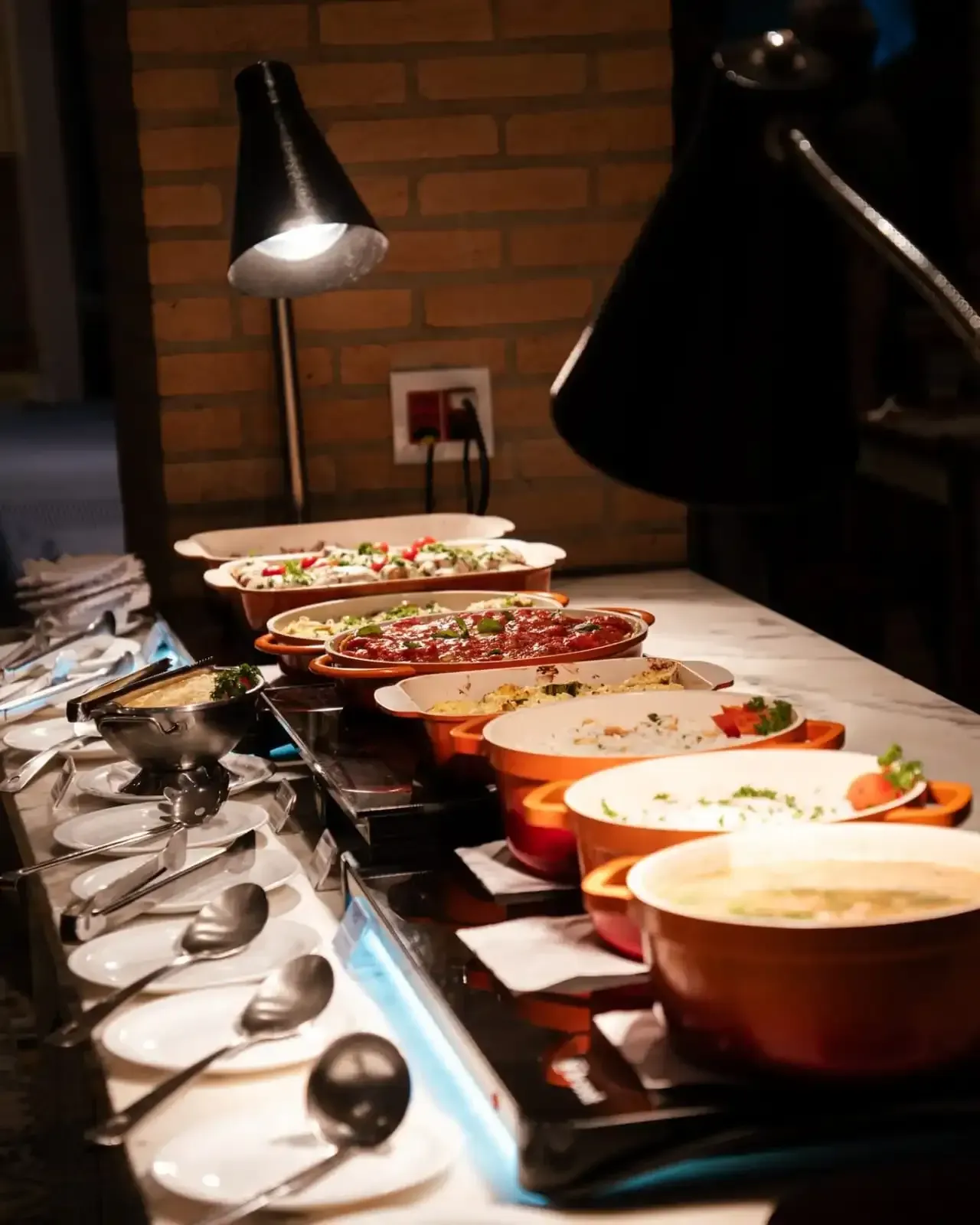 Buffet com diversos pratos aquecidos em um balcão de serviço.