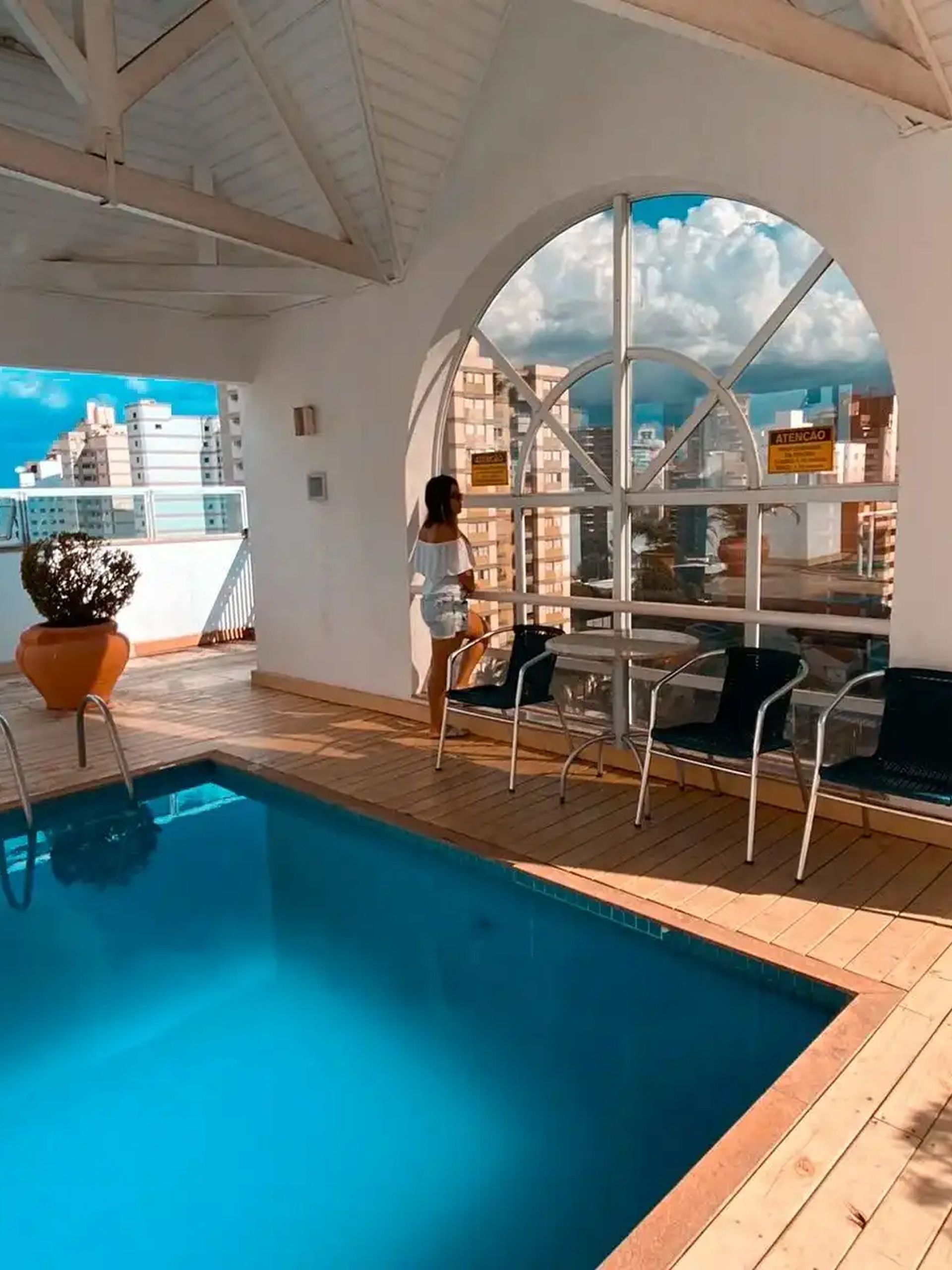 Spa coberto com piscina, espreguiçadeiras e vista para a cidade.