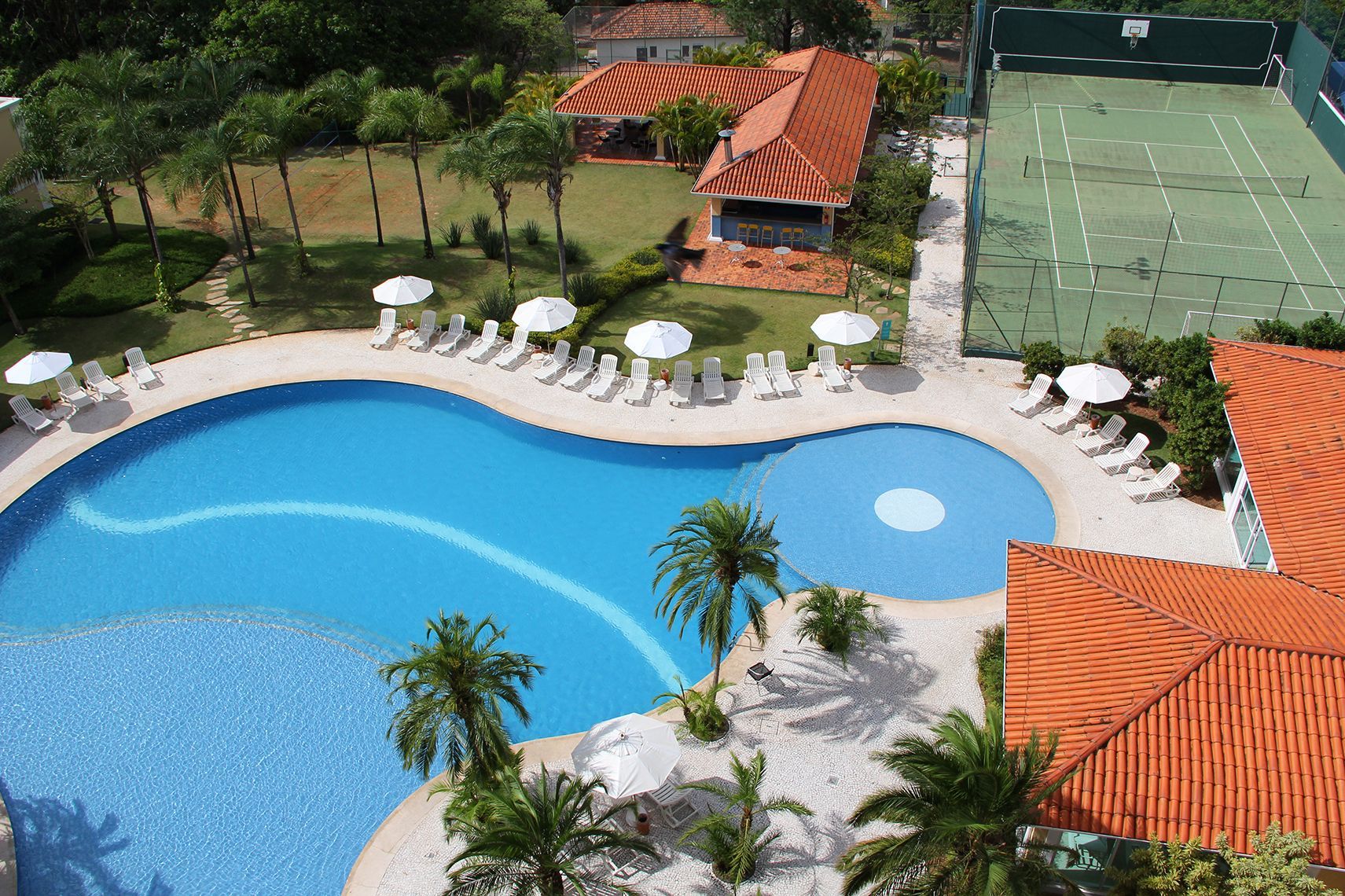Uma vista aérea de uma piscina e quadras de tênis