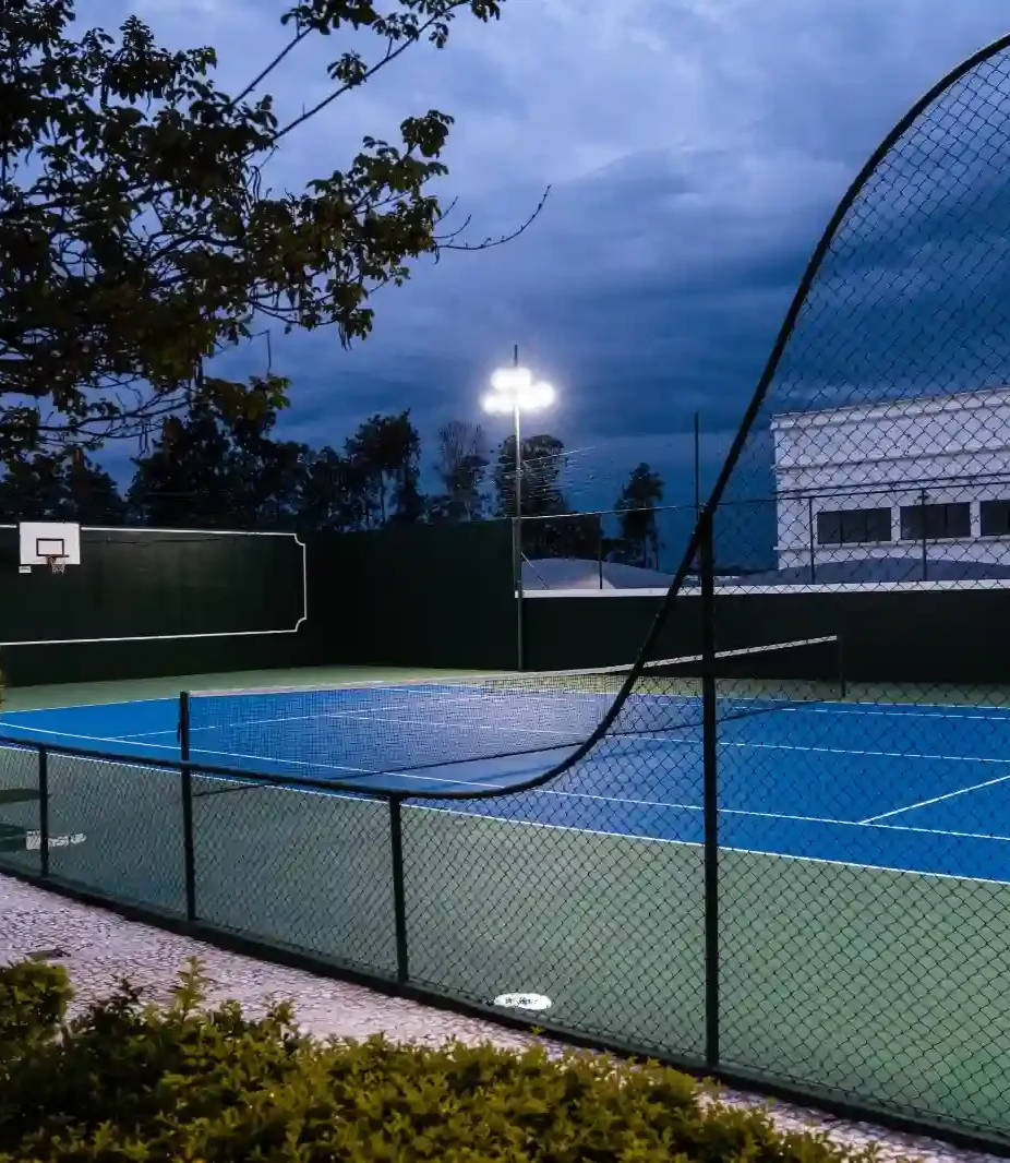 Instrutor auxiliando cliente com exercício para as pernas na academia. Outra pessoa observando.
