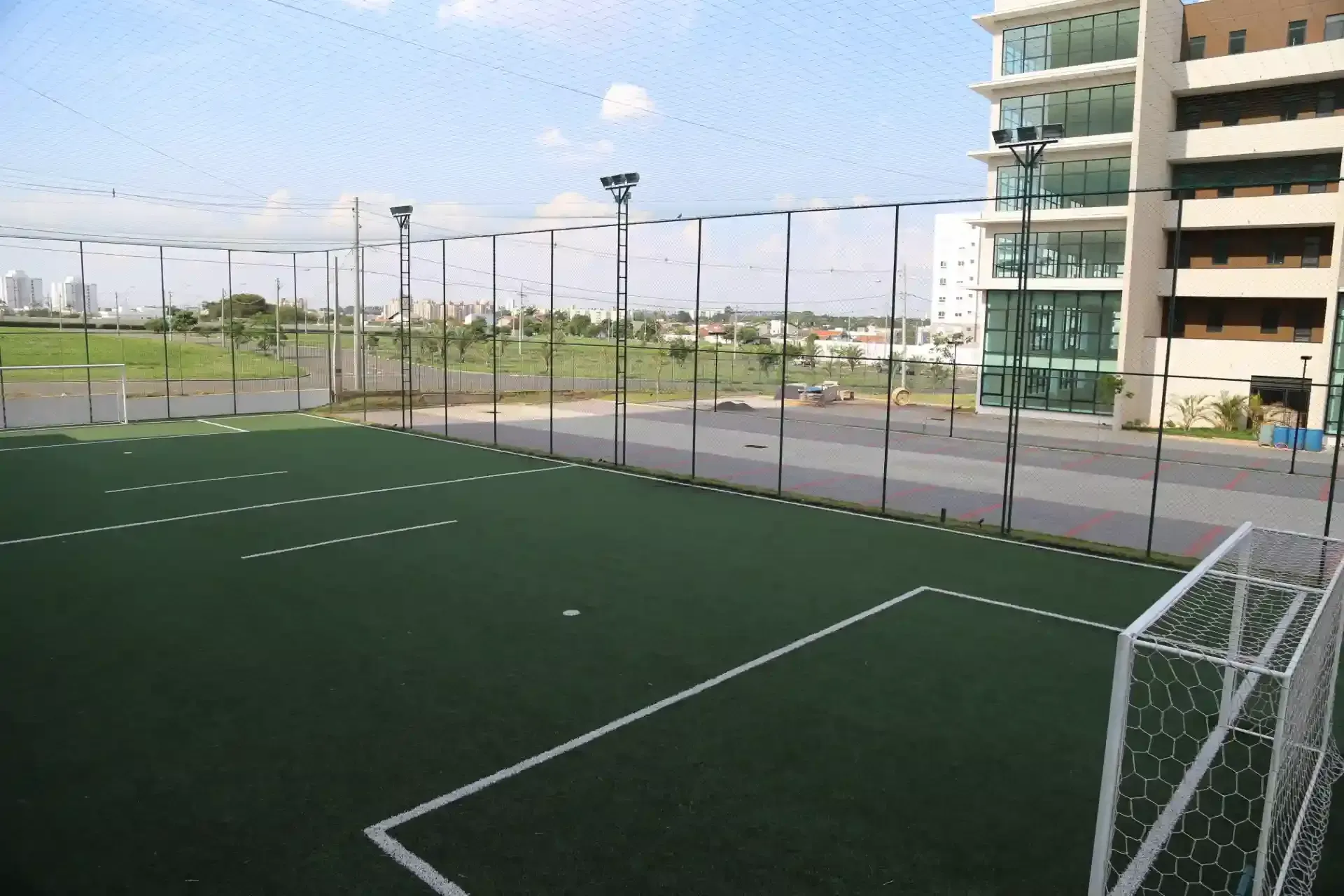 Interior da biblioteca com painéis de madeira, estantes de livros, assentos e grandes janelas.