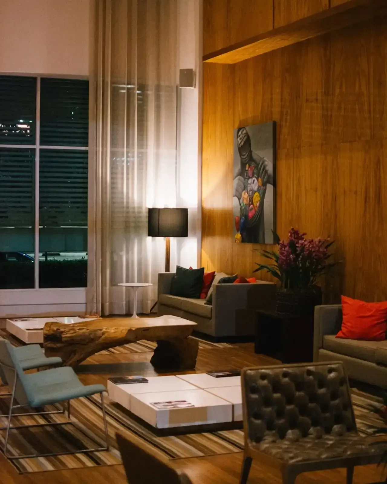 Sala de estar moderna com painéis de madeira, sofás, mesas de centro e uma grande janela.