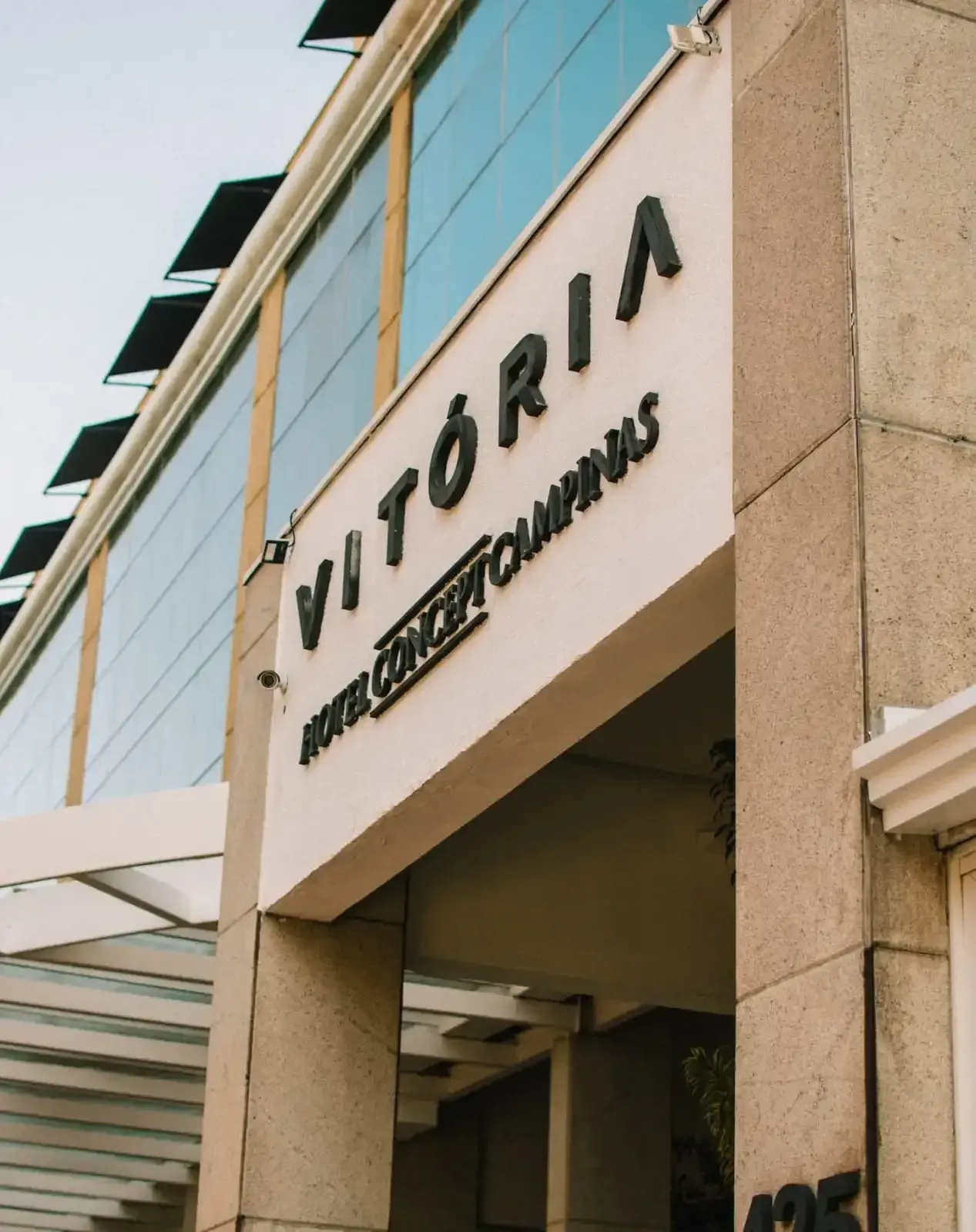 Hotel Vitória em Campinas, com letras pretas em fachada bege. Prédio moderno com janelas de vidro.