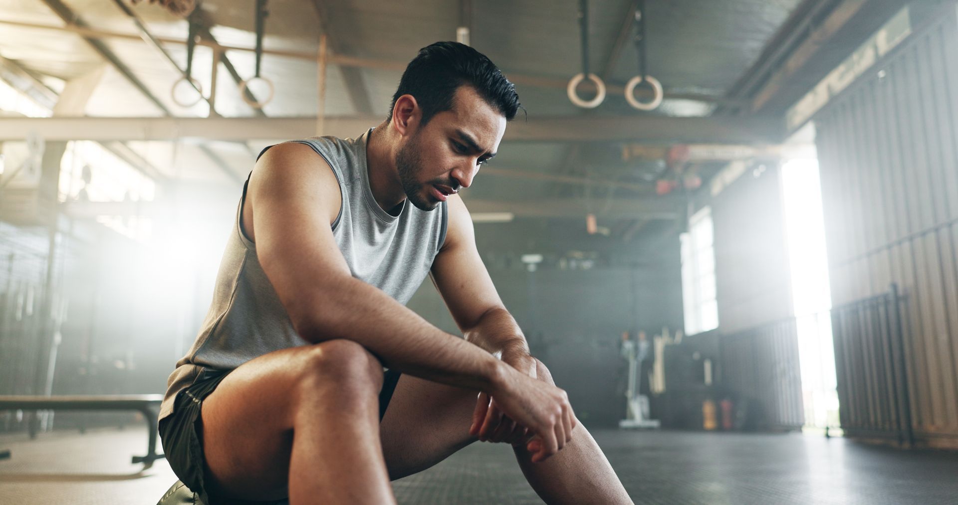 Tired athlete resting on a gym floor, head down after a workout.