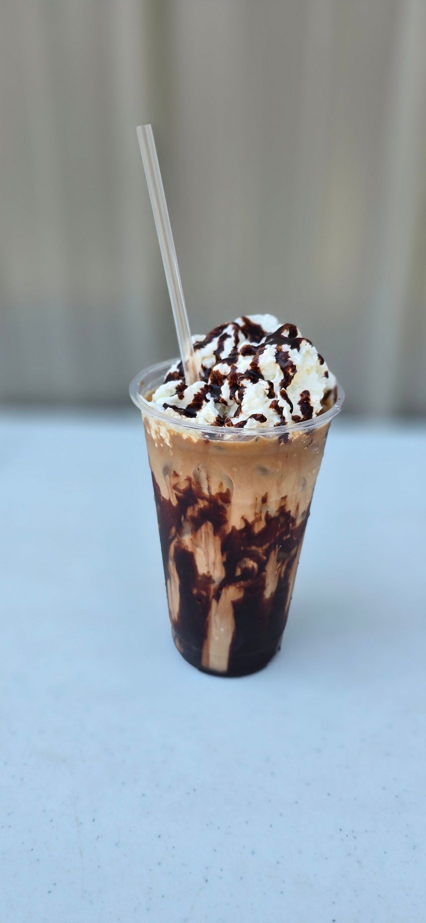 Mini donuts on a black wire rack, glazed in assorted colors and sprinkles, on a textured surface.