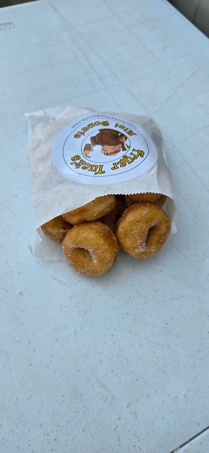 Powdered donuts with blueberries and mint on parchment paper.