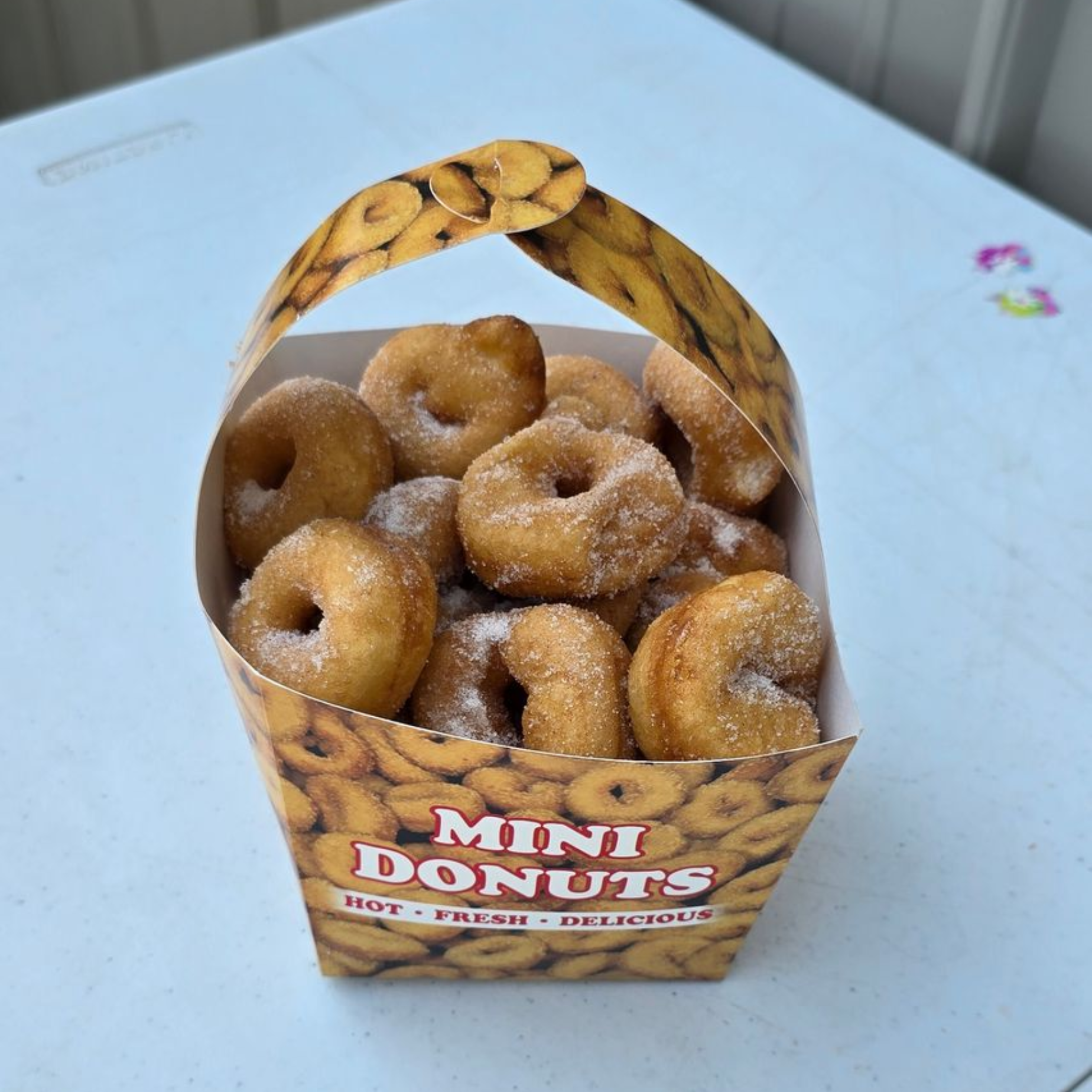 Mini donuts with colorful frosting and sprinkles on a wooden board.