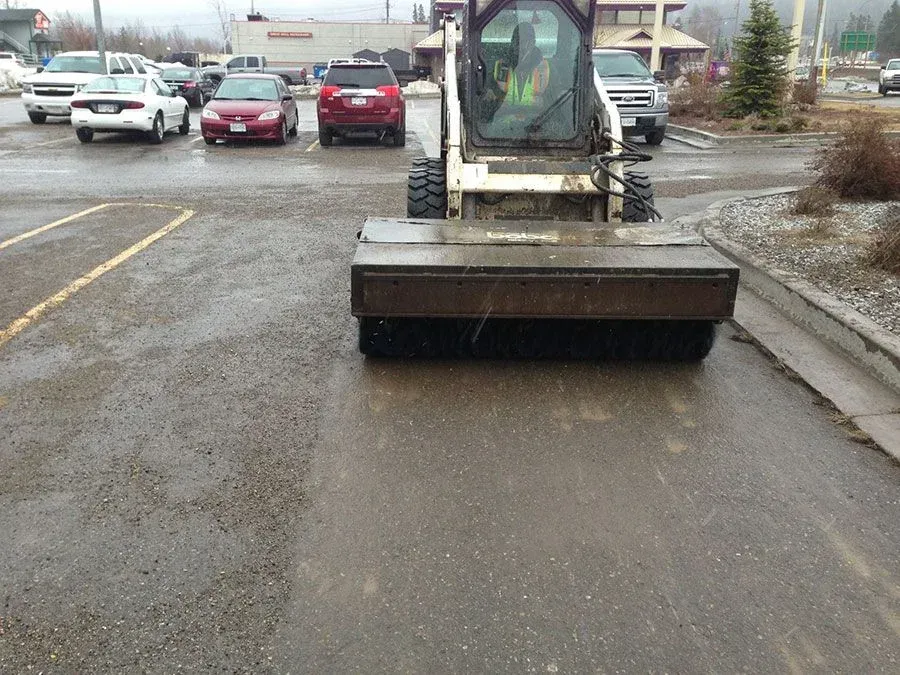 A bulldozer is parked in a parking lot with cars parked behind it