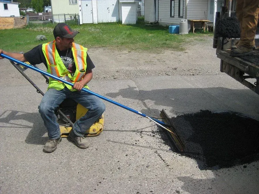 A man in a safety vest is digging a hole in the ground