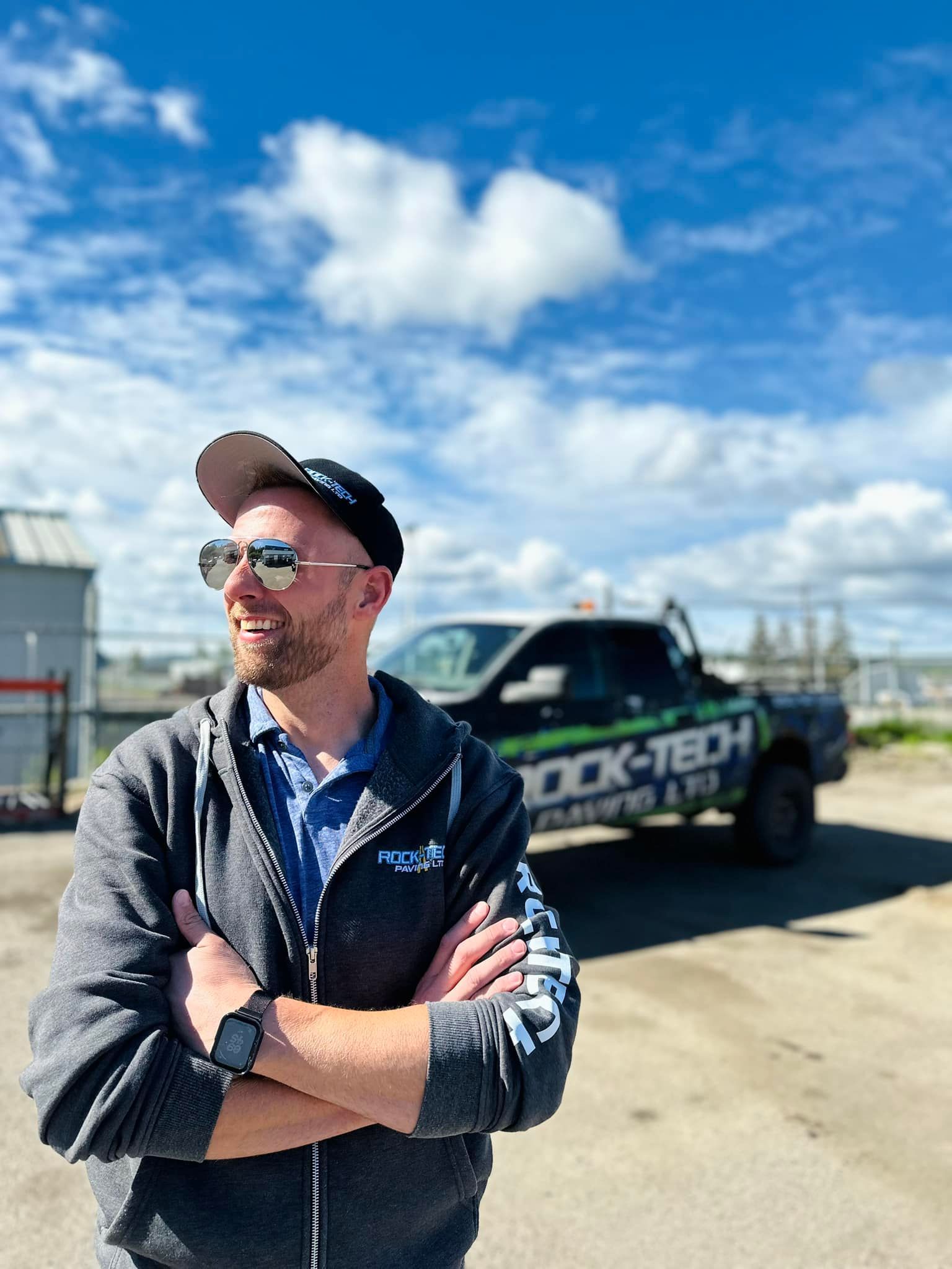 A man is standing in front of a truck with his arms crossed.