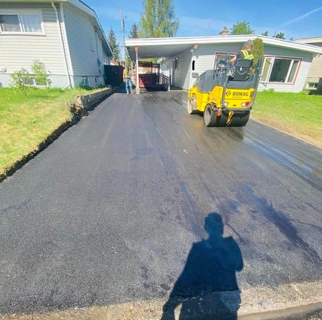 A man is standing in front of a house looking at a road being paved.