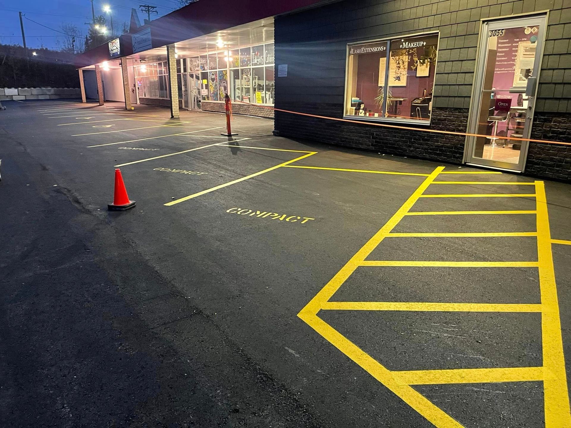 A parking lot with yellow lines and a red cone in front of a building.