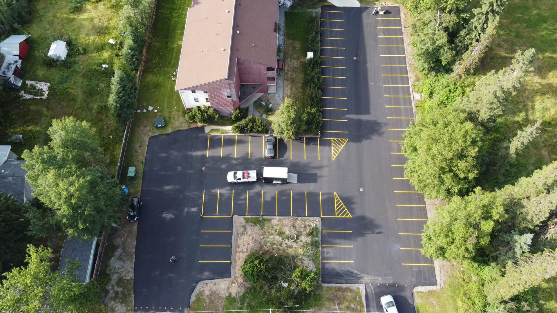 An aerial view of a parking lot with a house in the background.