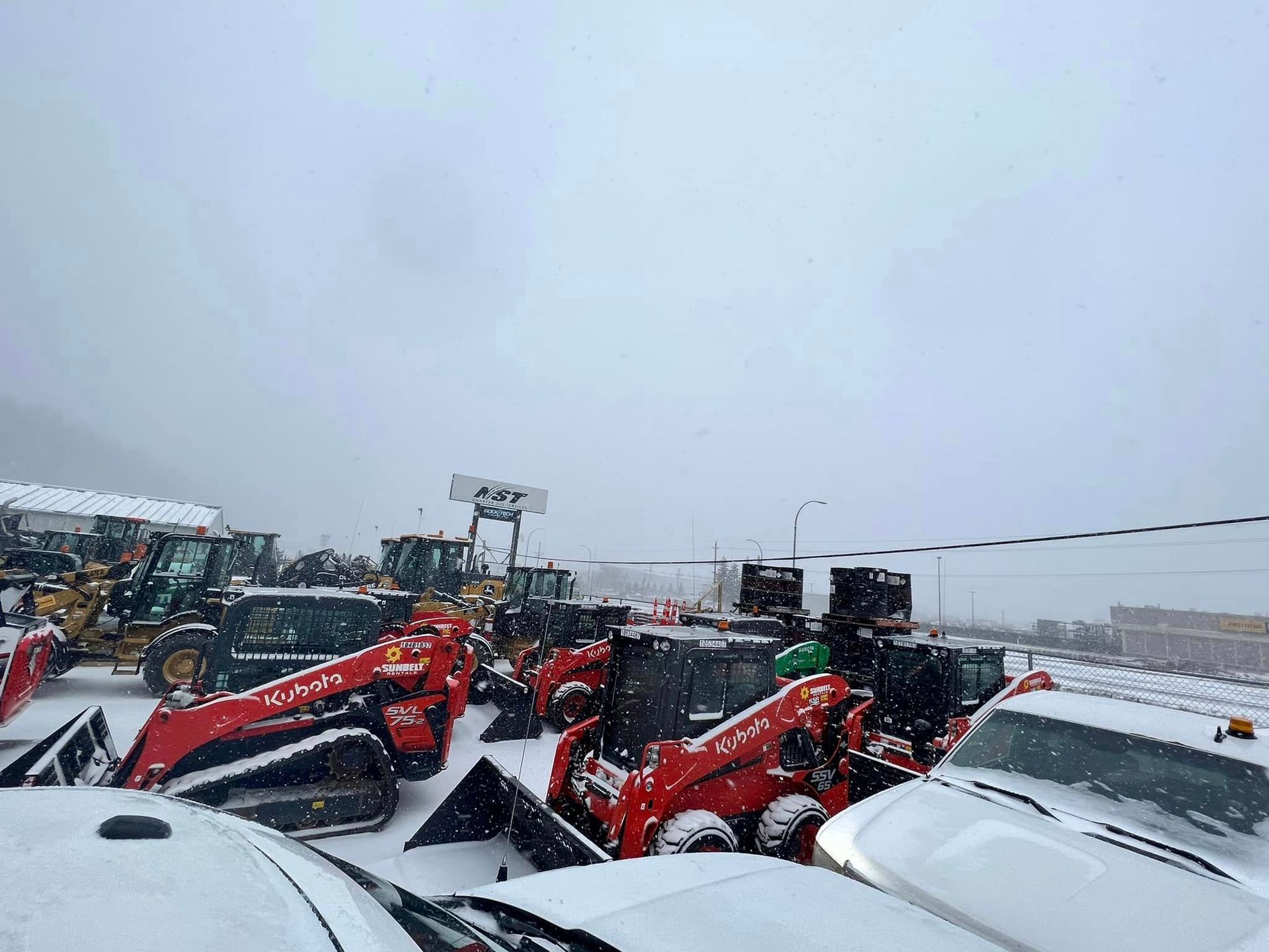 A lot of tractors are parked in the snow.