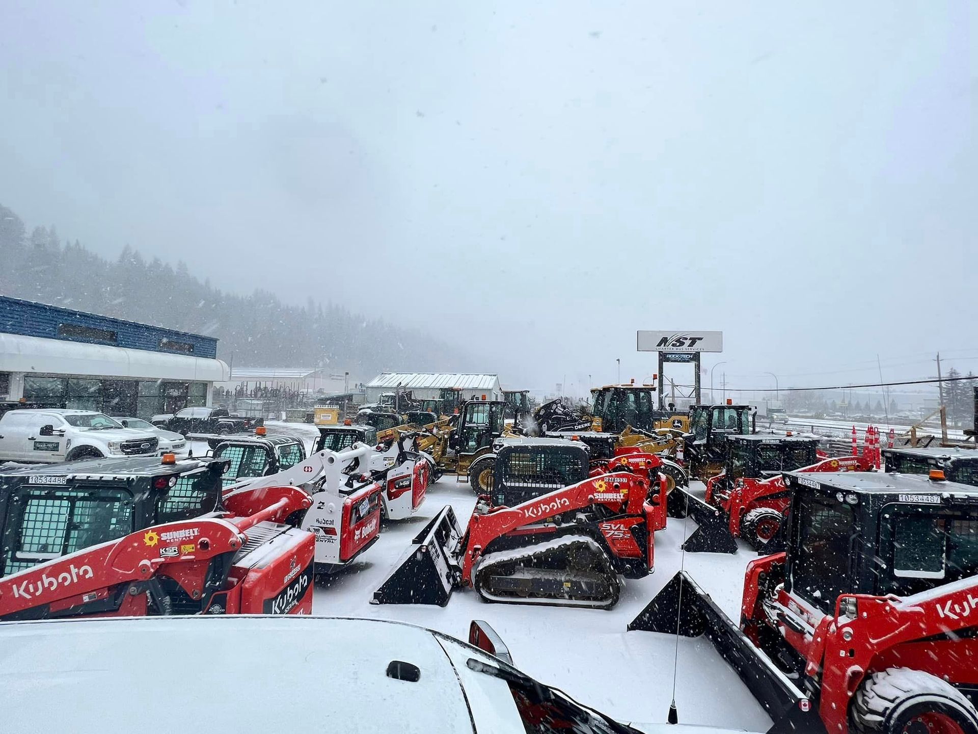 A lot of tractors are parked in the snow.