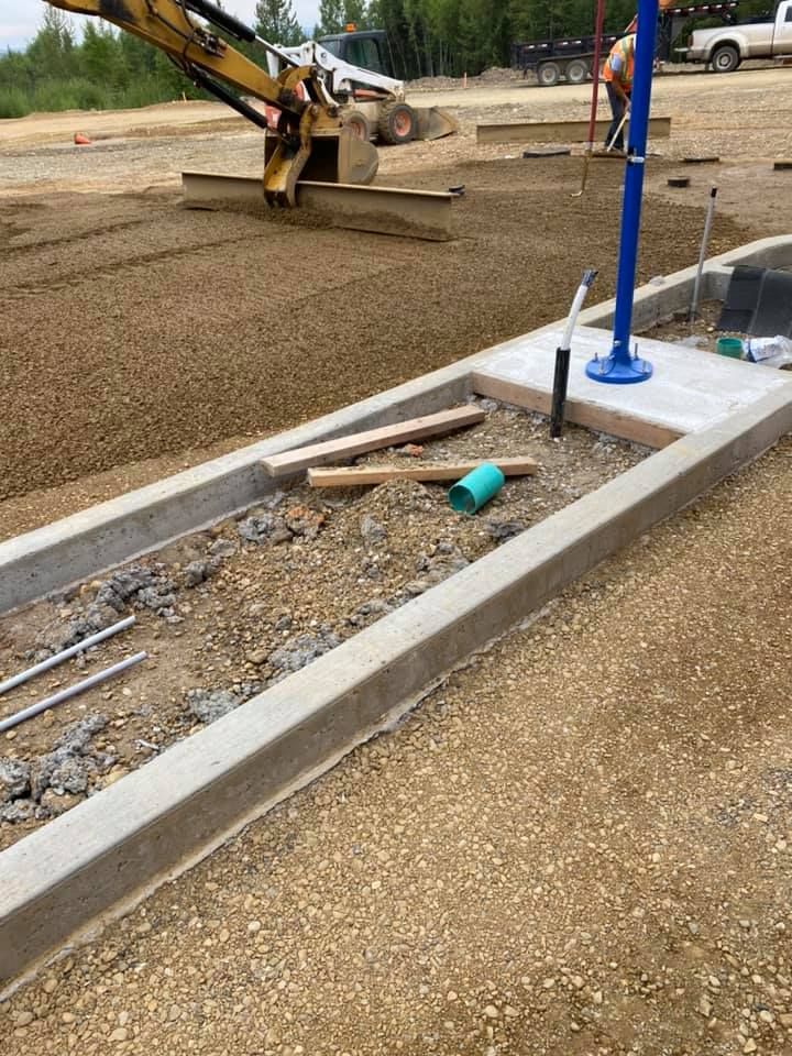 A construction site with a bulldozer and a concrete curb.