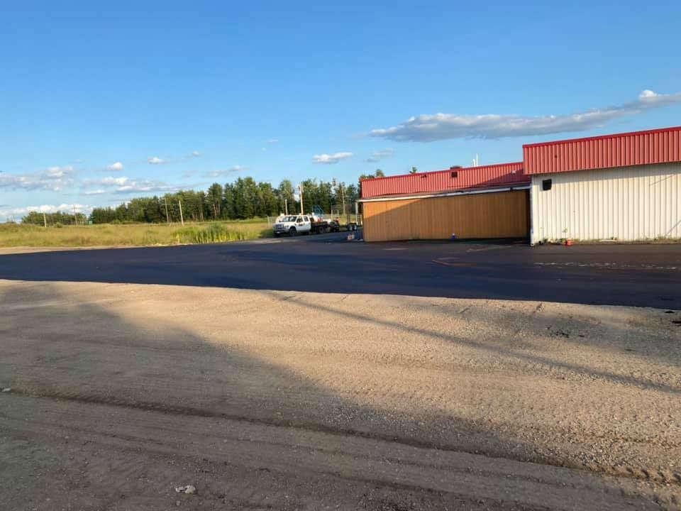 A large building with a red roof is sitting in the middle of a parking lot.