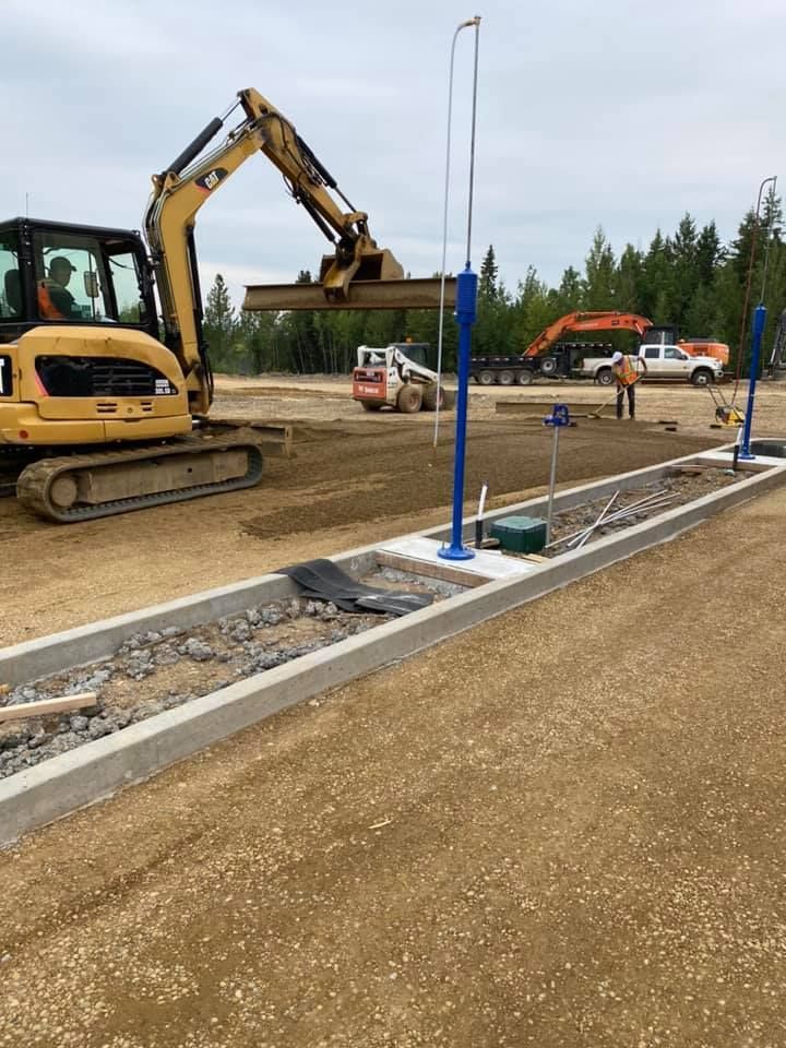 A construction site with a yellow excavator and a blue pole.