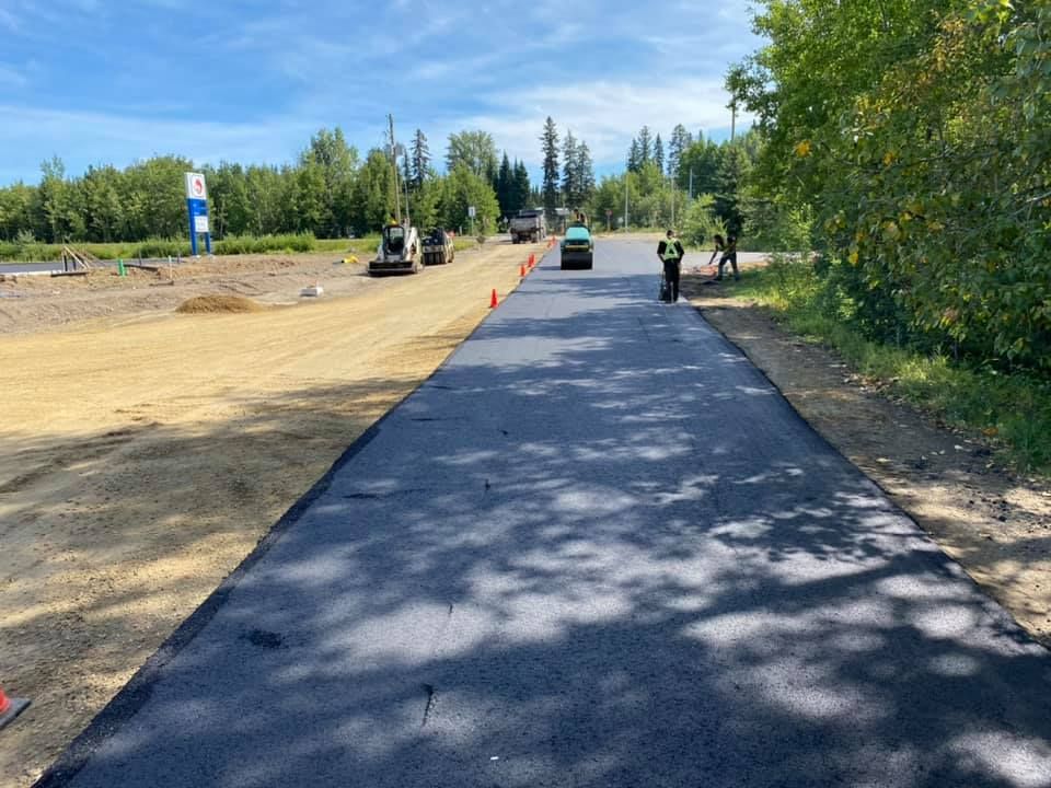 A man in a yellow vest is standing on the side of a road.