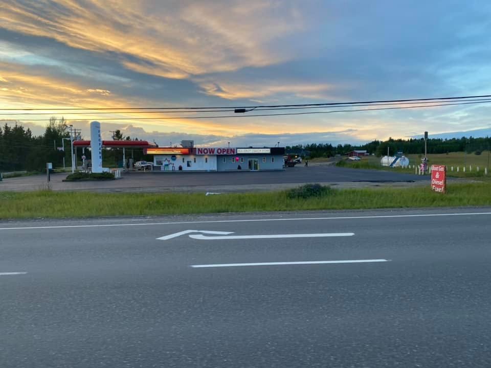 A gas station is located on the side of the road at sunset.
