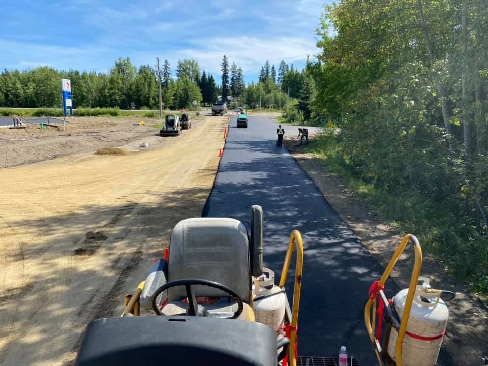A tractor is driving down a dirt road.