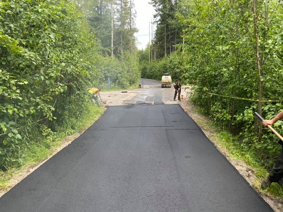 A man is standing on the side of a road holding a shovel.