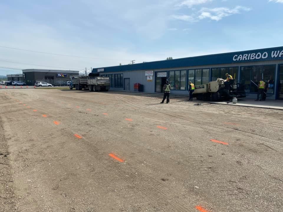 A group of people are working on a road in front of a building.