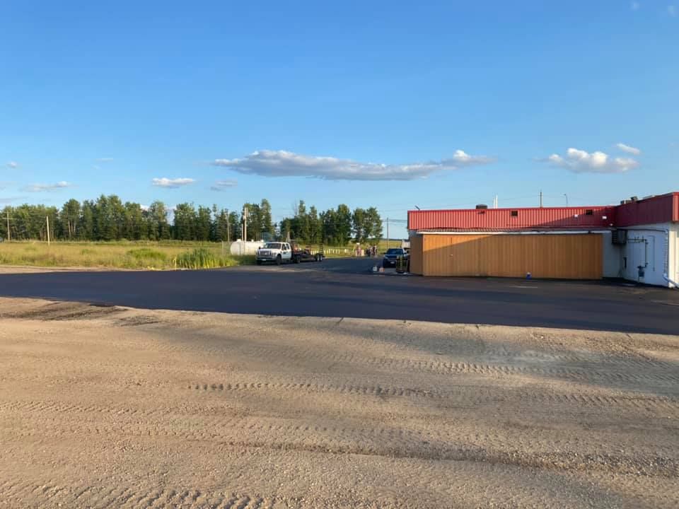 A large building with a red roof is sitting in the middle of a dirt field.