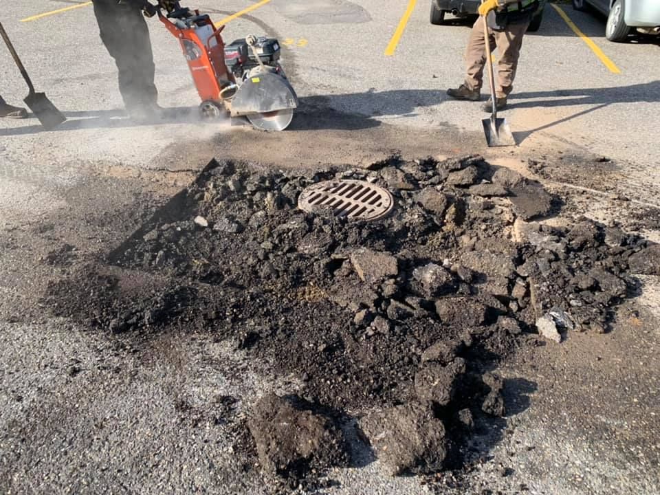 A manhole cover is being removed from the ground