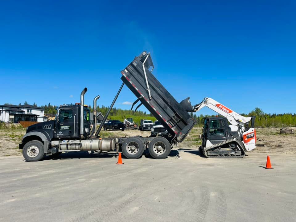 A dump truck is being towed by a bulldozer in a parking lot.