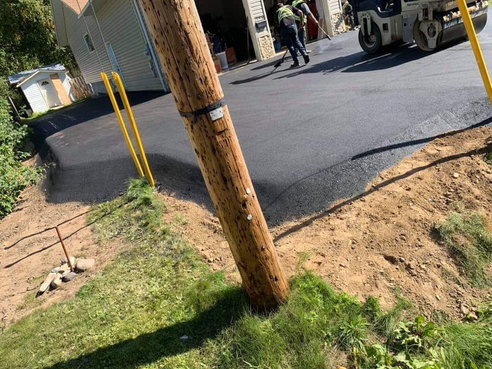 A man is walking down a road next to a telephone pole.