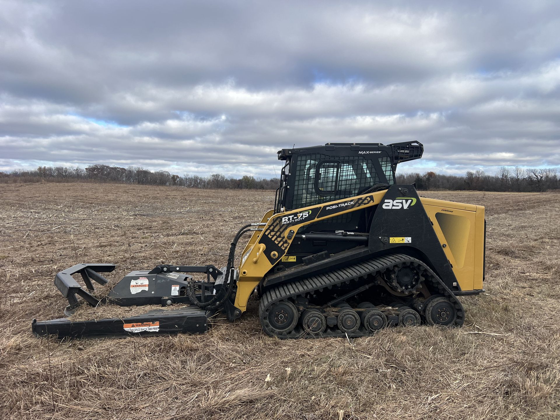 Yellow excavator on a pile of gravel, with a forest background.