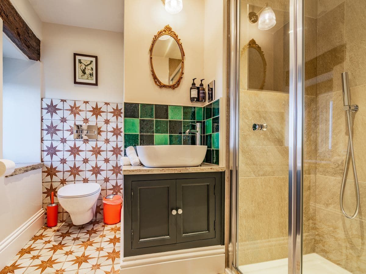 Bathroom with patterned tile, green and gold accents, and a glass shower.