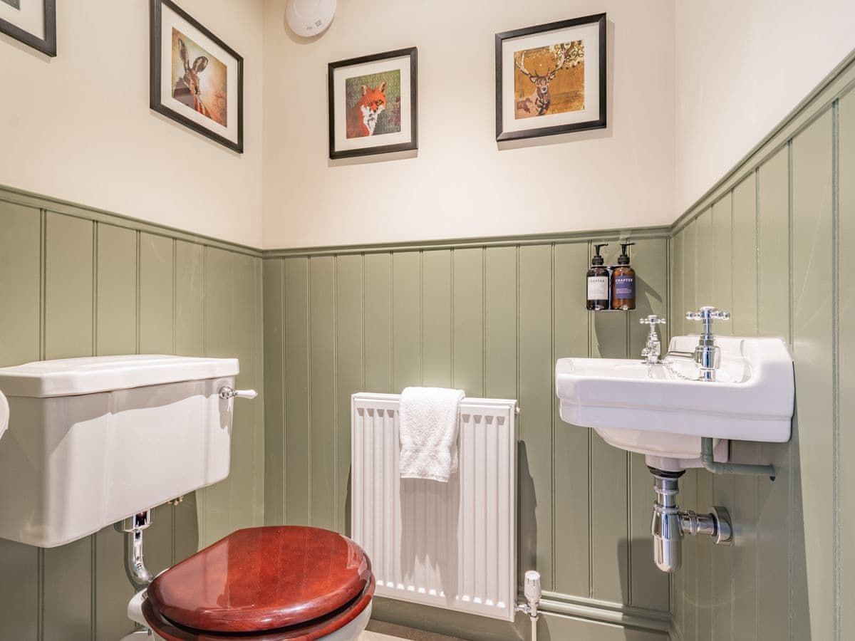 Small bathroom with green paneling, white sink and toilet, and fox art.