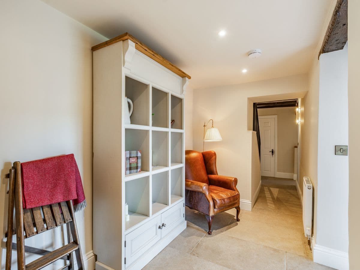 Hallway with white shelving unit, leather armchair, and wooden folding ladder with red towel.