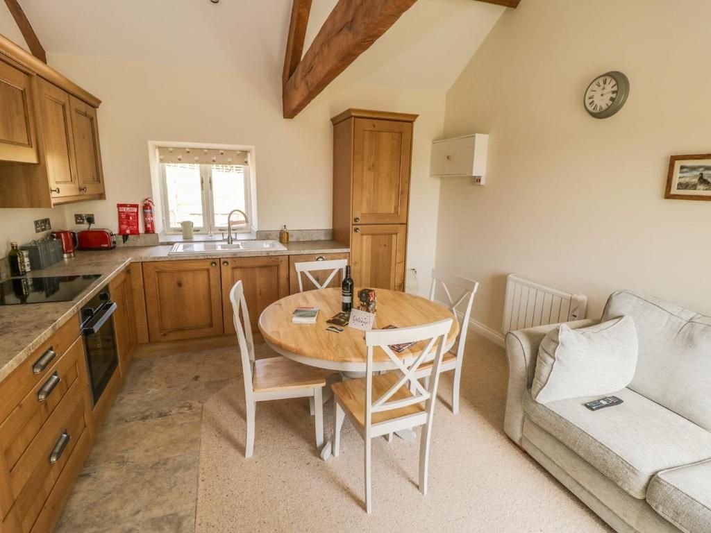 Kitchen with wooden cabinets, round table with chairs, and a small sofa.