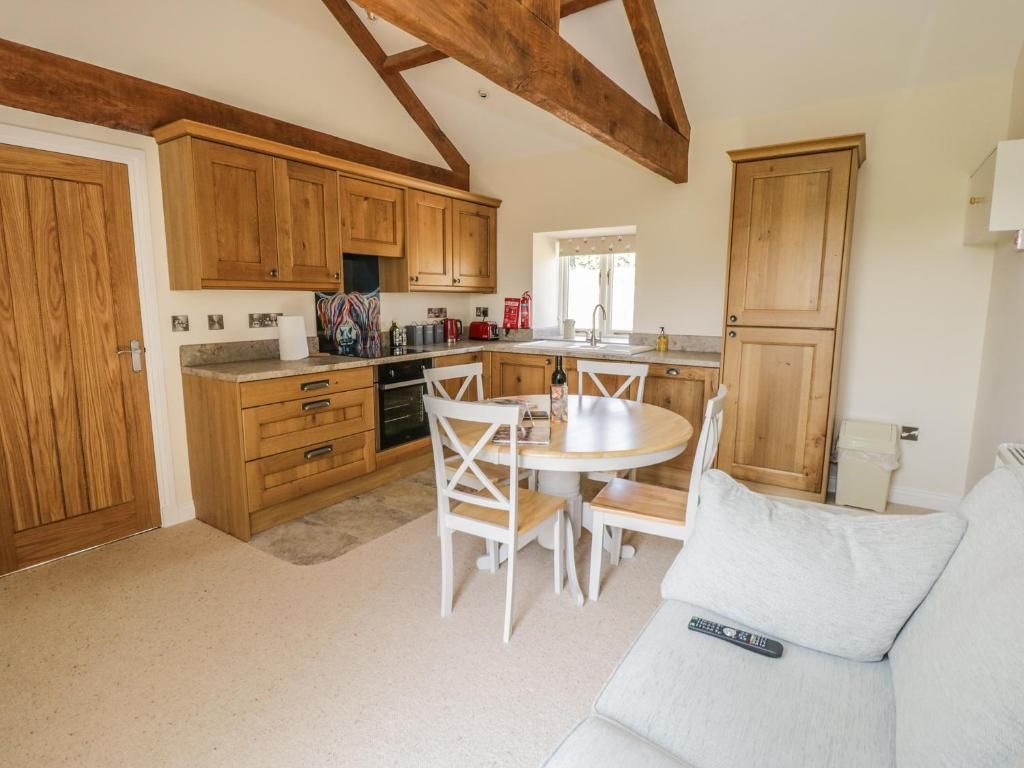 Kitchen with wooden cabinets, table, and chairs; sofa in the foreground, window and door.