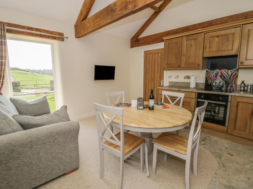 Cozy cottage interior with kitchen, dining area, and sofa. Wooden beams, light colors, and a view.
