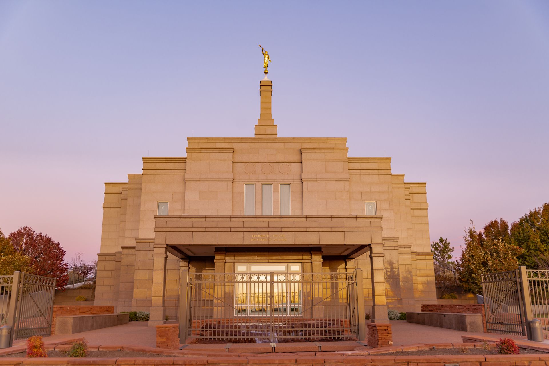 Beige temple with a golden angel statue at sunset.