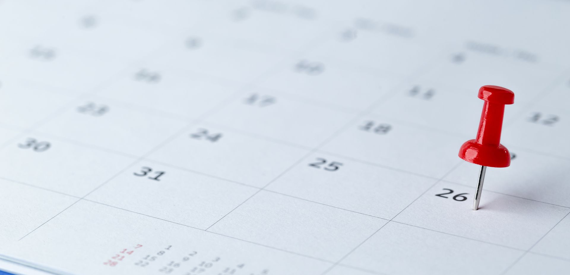 A calendar page with a red pushpin on the 26th day.