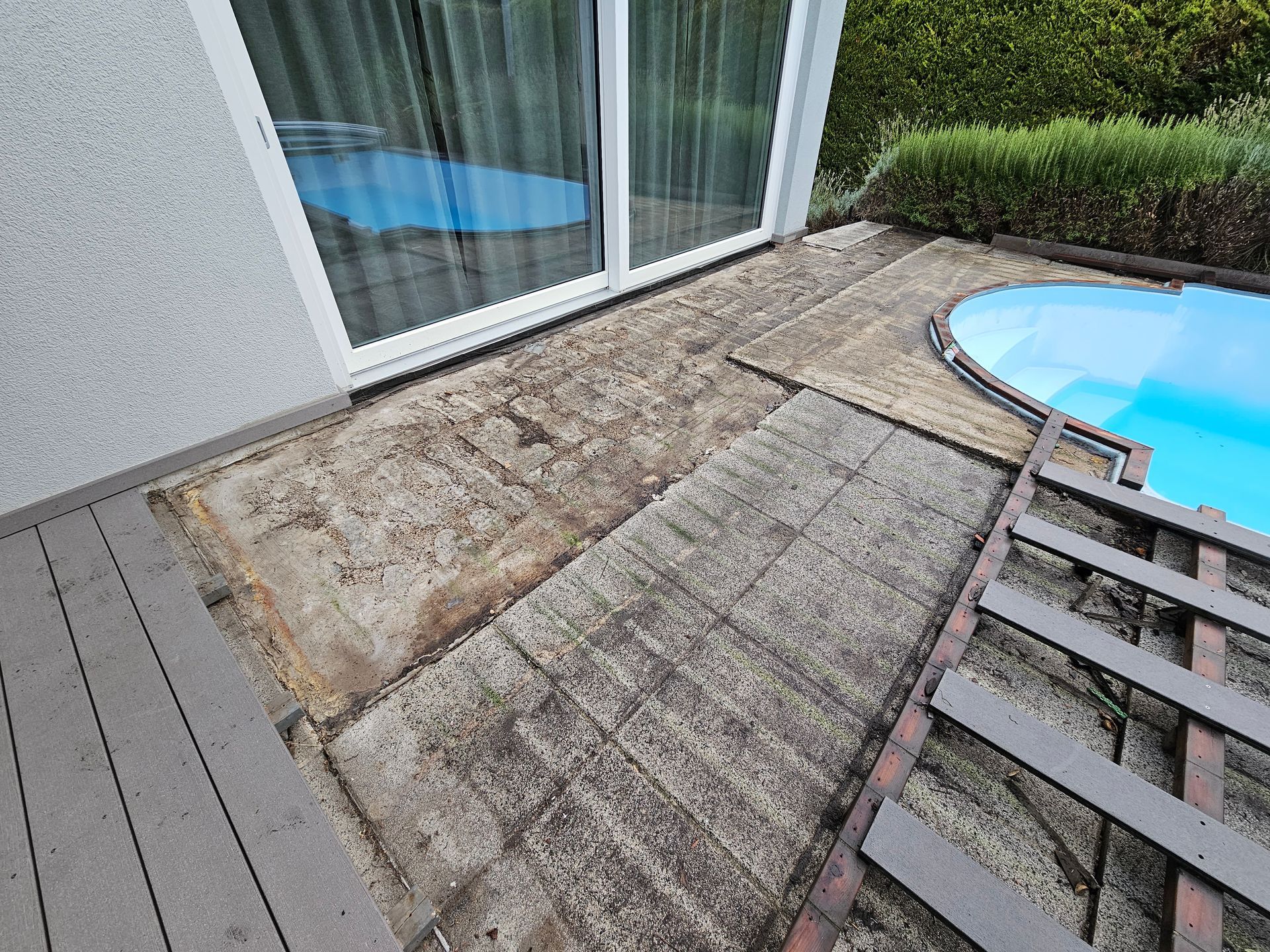 Ein Terrassenbereich, der derzeit renoviert wird und aus Holzdielen, freiliegenden Betonabschnitten und einem kleinen Hinterhofpool besteht.