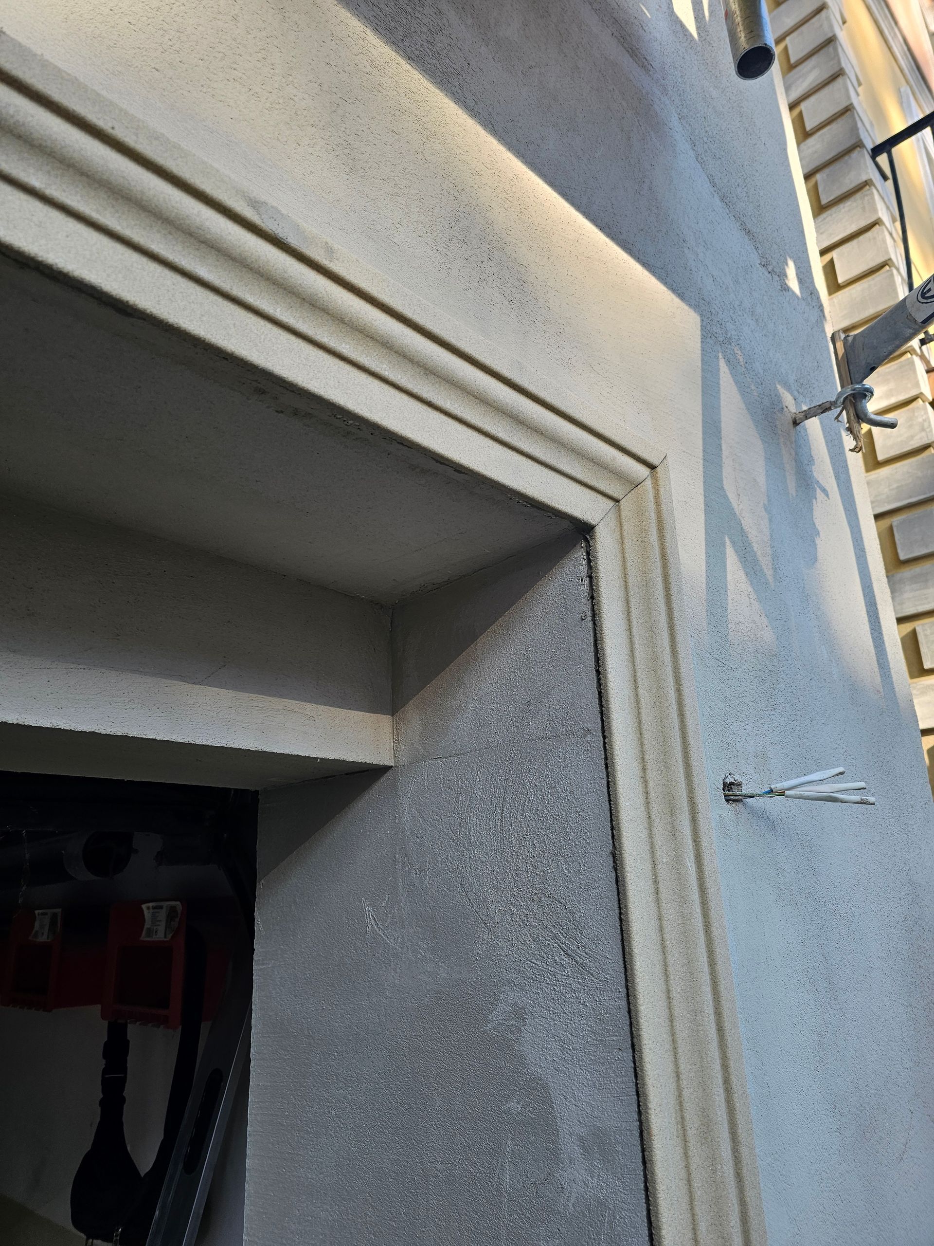 Nahaufnahme eines Türrahmens mit Zierleisten, die strukturierte graue Wände und helle Zierleisten zeigt.