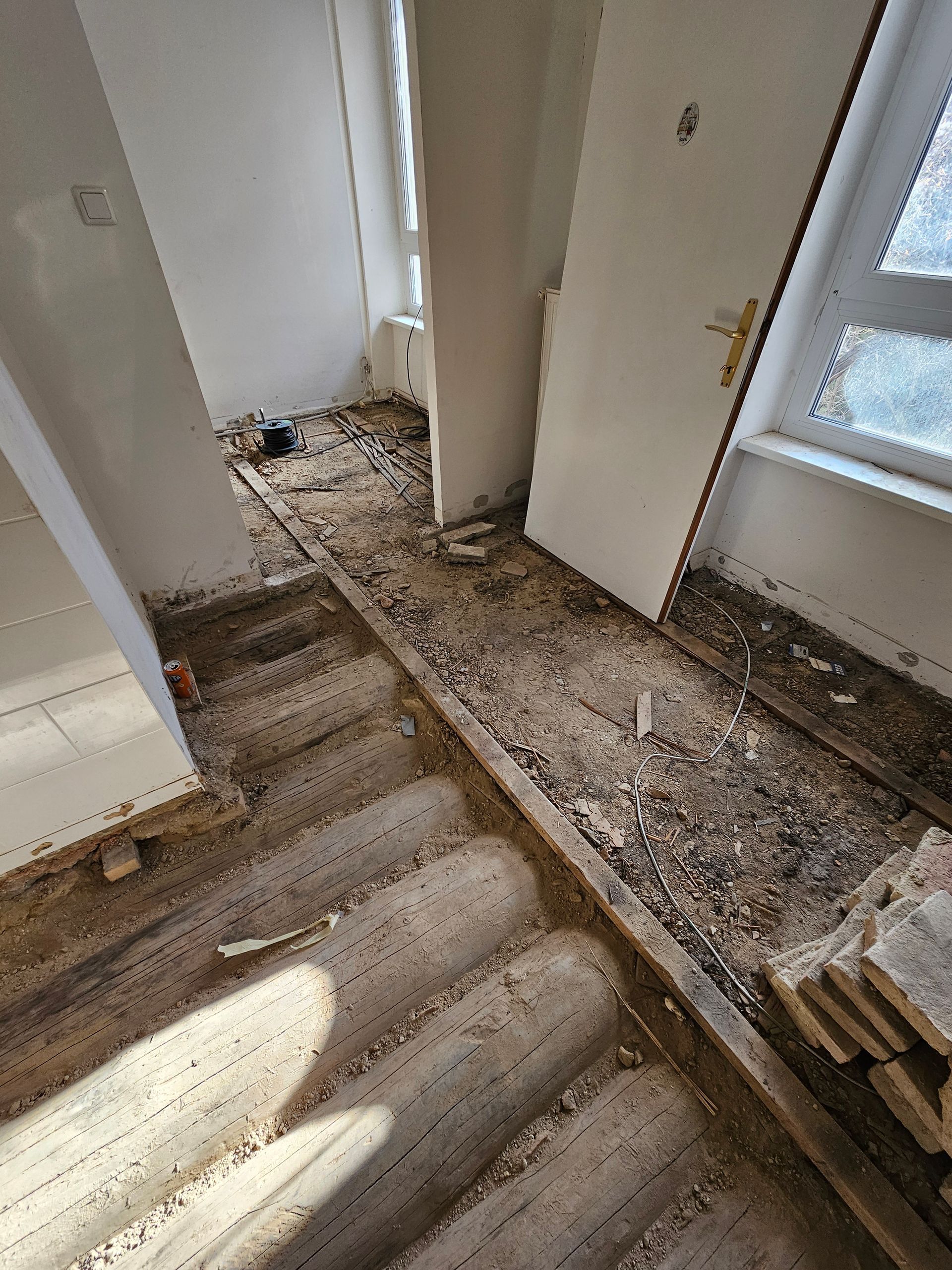 Treppe und Boden eines Hauses, das renoviert wird und mit Bauschutt und Holzspänen bedeckt ist.