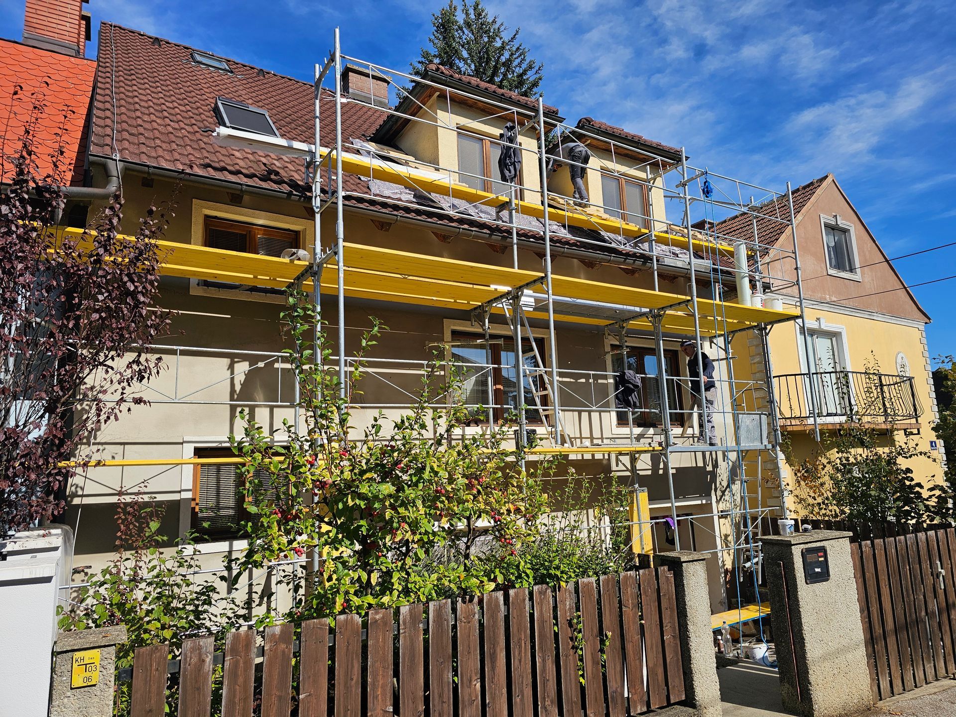 Ein beigefarbenes, mehrstöckiges Haus, dessen Fassade renoviert wird; an der Vorderseite ist ein Gerüst aufgebaut.