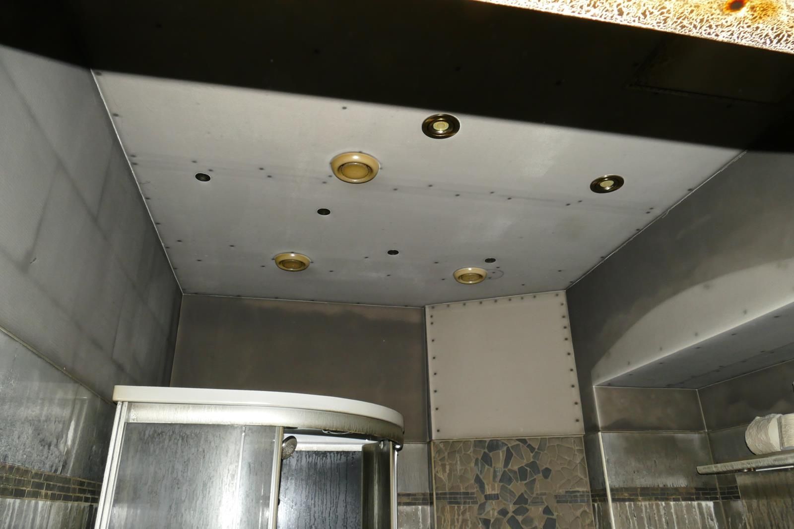 Eine Badezimmerdecke mit eingebauten Einbaustrahlern, Gipskartonplatten und sichtbaren Schraubenköpfen.