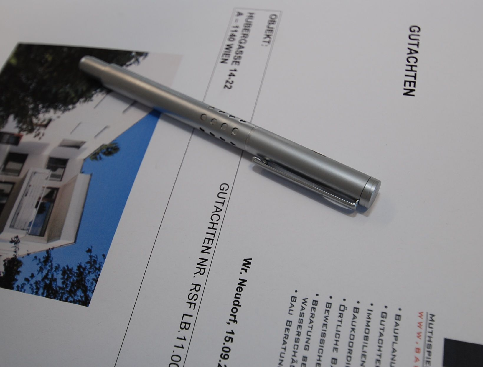 Ein silberner Stift ruht auf einem Dokument mit dem Titel „Gutachten“